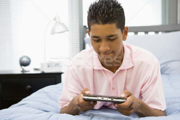 Teenage Boy Lying On Bed Playing Video Game Stock photo © monkey_business