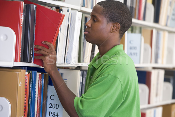 Stock photo: University student slecting book from library shelf