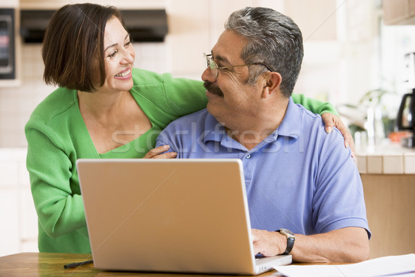 Couple in kitchen with laptop smiling Stock photo © monkey_business