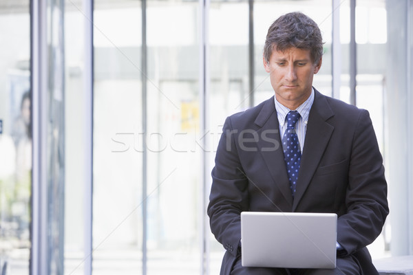 Businessman sitting in office lobby using laptop Stock photo © monkey_business