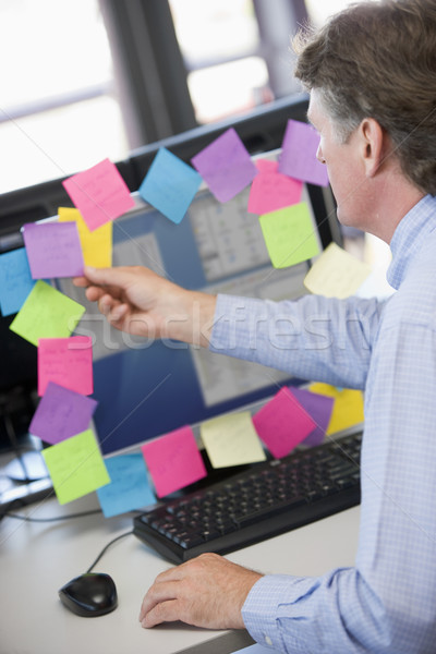 Businessman in office at monitor with notes on it Stock photo © monkey_business