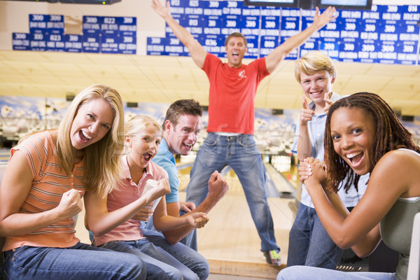 Family in bowling alley with two friends cheering and smiling Stock photo © monkey_business