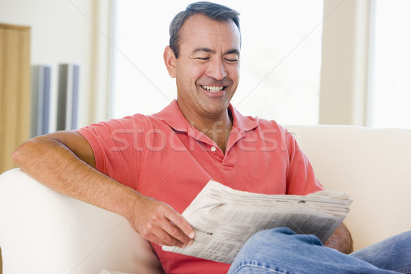 Man reading newspaper in living room smiling Stock photo © monkey_business