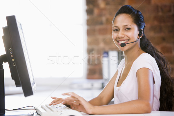 Businesswoman in office wearing headset and typing on computer s Stock photo © monkey_business