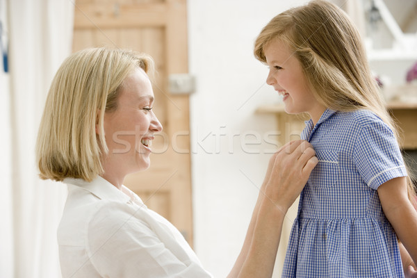 Woman in front hallway fixing young girl's dress and smiling Stock photo © monkey_business