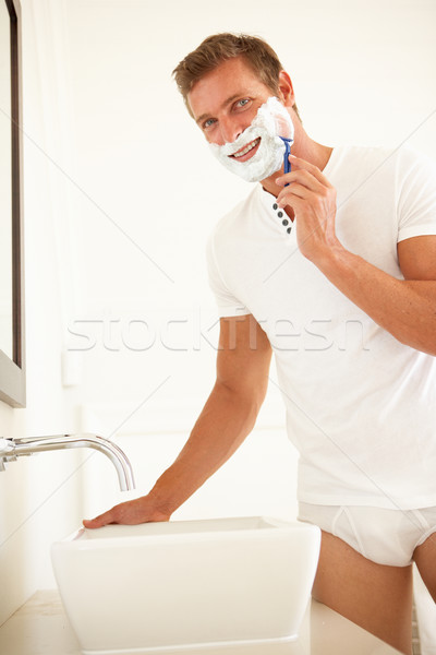 Young Man Shaving In Bathroom Mirror Stock photo © monkey_business