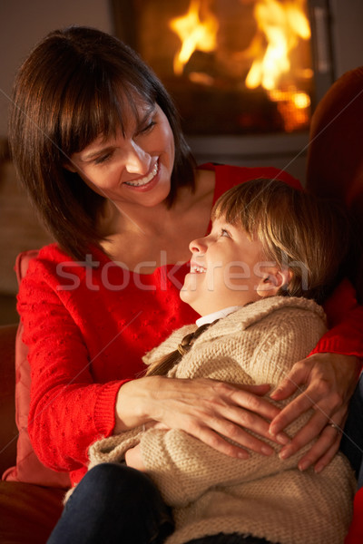 Mother And Daughter Relaxing On Sofa By Cosy Log Fire Stock photo © monkey_business