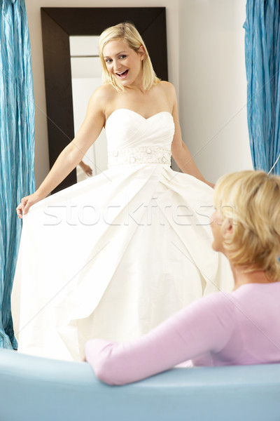 Bride Trying On Wedding Dress With Sales Assistant Stock Photo