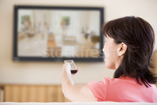 Woman watching television using remote control Stock photo © monkey_business