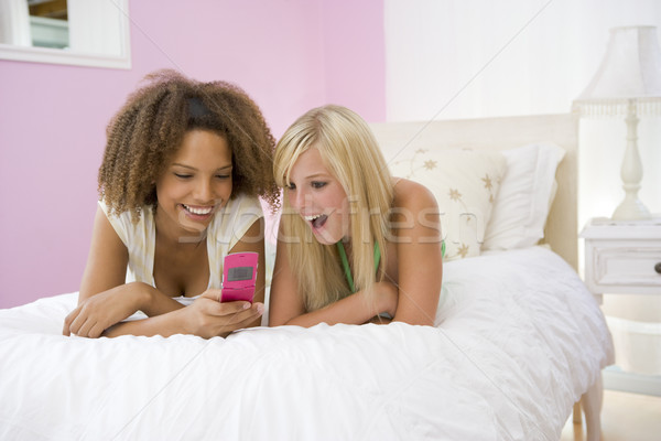 Tinilányok ágy mobiltelefon boldog barátok tini Stock fotó © monkey_business