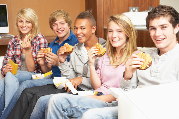 Group Of Teenage Friends Sitting On Sofa At Home Eating Fast Foo Stock photo © monkey_business