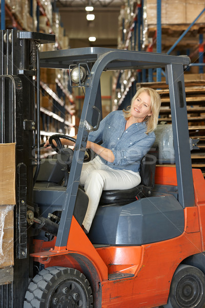 Stock photo: Woman Driving Fork Lift Truck In Warehouse