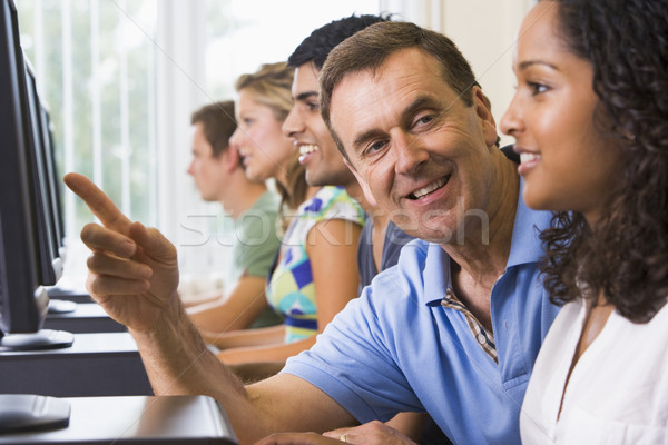 Stock photo: Teacher assisting college student in a computer lab