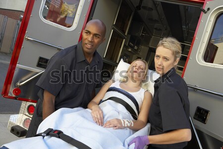 Hospital doctor taking notes as paramedics arrive with patient Stock photo © monkey_business