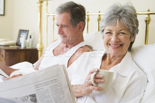 Stock photo: Couple in bedroom with coffee and newspapers smiling