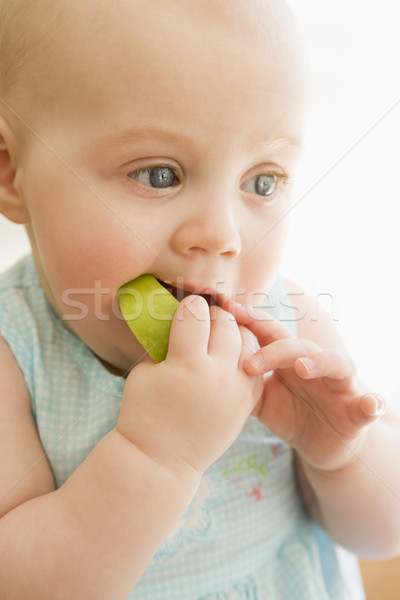 Stock photo: Baby eating apple indoors