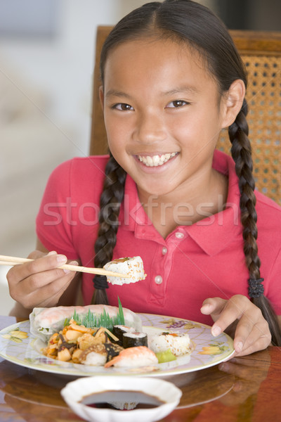 Stock photo: Young girl in dining room eating Chinese food smiling