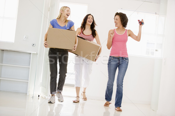 Stock photo: Three girl friends moving into new home smiling