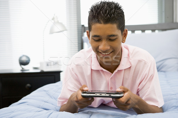 Teenage Boy Lying On Bed Playing Video Game Stock photo © monkey_business