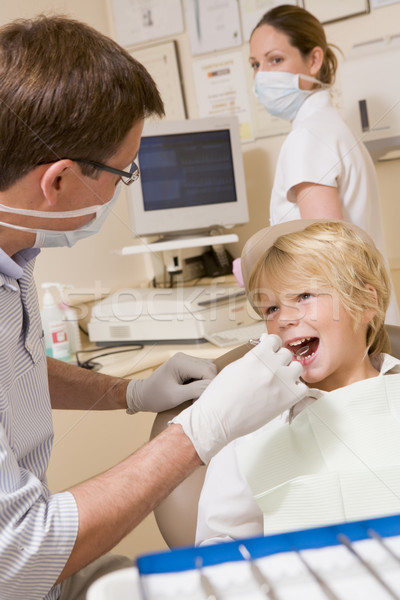 Dentist and assistant in exam room with young boy in chair Stock photo © monkey_business