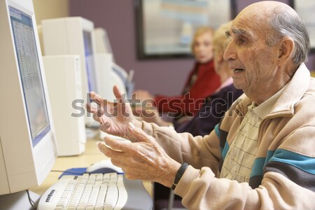 A teacher talks to a schoolgirl using a computer in a high schoo Stock photo © monkey_business