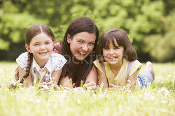 Mother and daughters lying outdoors with flower smiling Stock photo © monkey_business