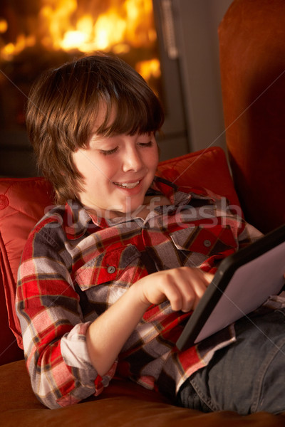 Young Boy Relaxing With Tablet Computer By Cosy Log Fire Stock photo © monkey_business