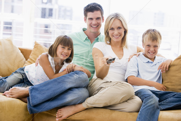 Stock photo: Family sitting in living room with remote control smiling
