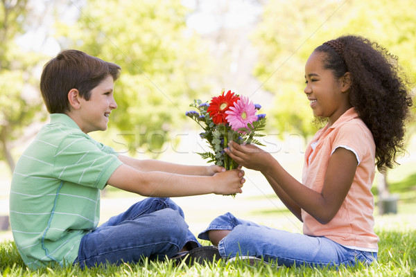 Stock photo: Young boy giving young girl flowers and smiling