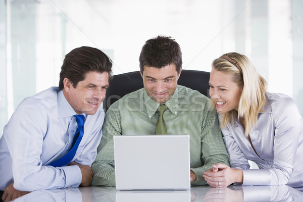 Three businesspeople in office with laptop smiling Stock photo © monkey_business