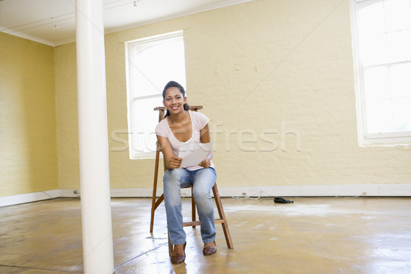 Woman sitting on ladder in empty space holding paper smiling Stock photo © monkey_business