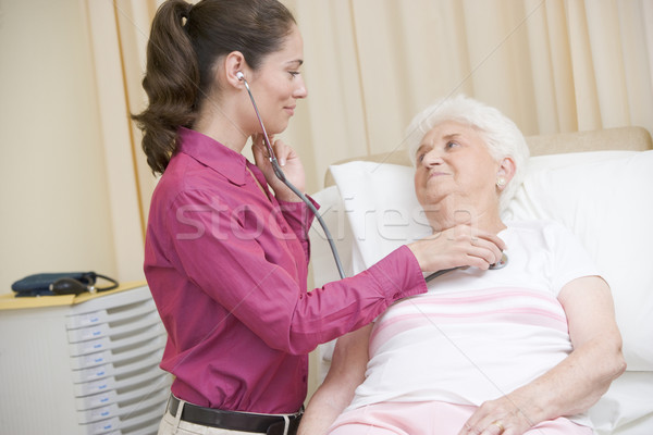 Stock photo: Doctor giving checkup with stethoscope to woman in exam room smi