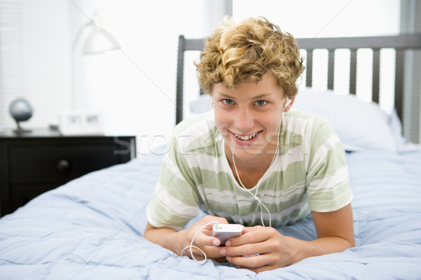 十幾歲的男孩 床 聽 mp3播放器 頭戴耳機 青少年 商業照片 © monkey_business