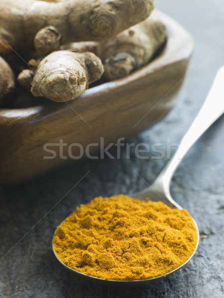 Stock photo: Spoon of Turmeric Powder with fresh Turmeric Root