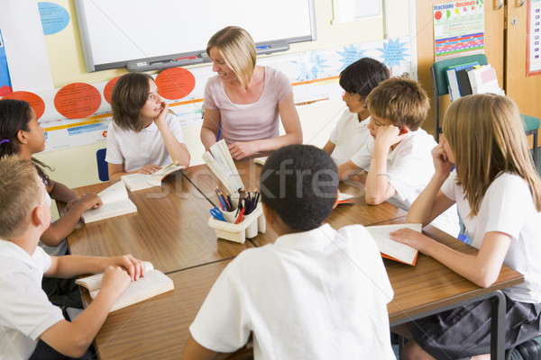Schoolchildren and their teacher reading books in class Stock photo © monkey_business
