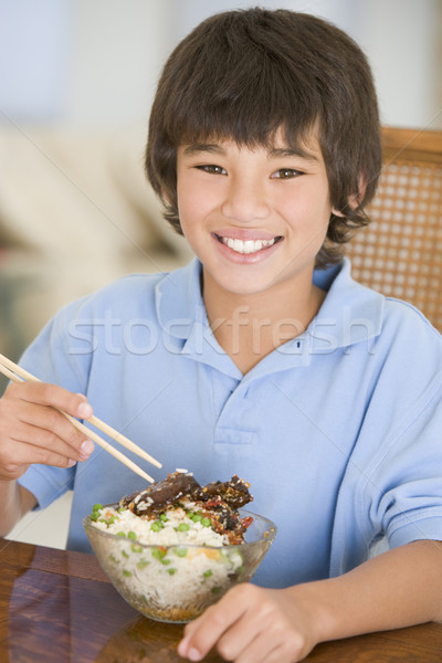 Stock photo: Young boy in dining room eating chinese food smiling