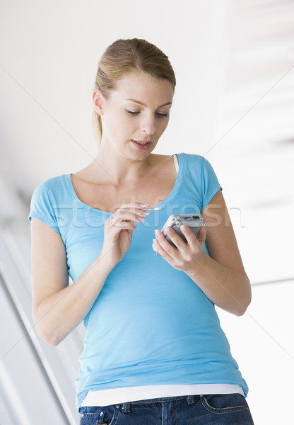 Woman standing in corridor using personal digital assistant Stock photo © monkey_business