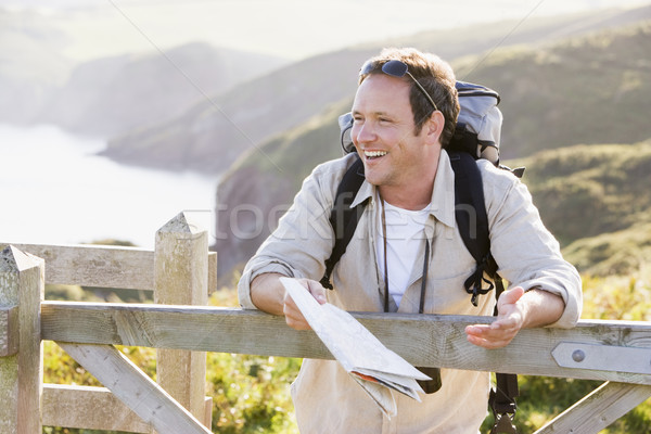 Stock photo: Man relaxing on cliffside path holding map and laughing