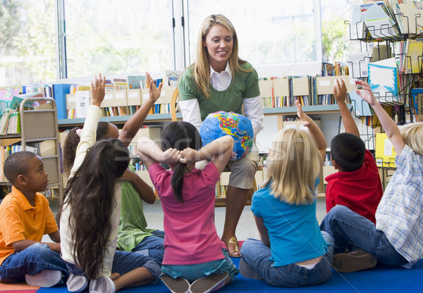 Kindergarten teacher and children with hands raised in library Stock photo © monkey_business