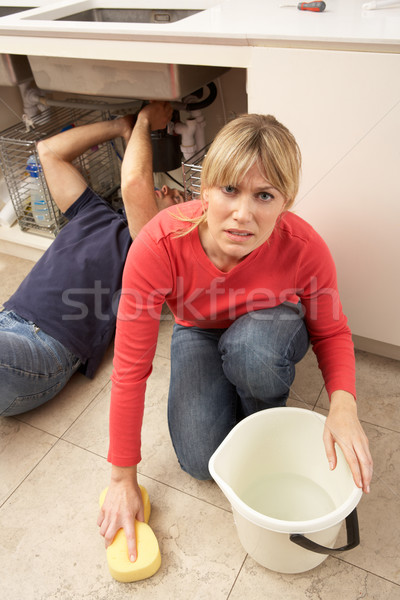 Woman Mopping Up Leaking Sink Whilst Plumber Works Stock photo © monkey_business