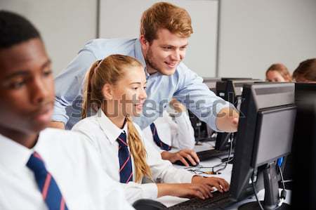 Stock photo: Girls using computers in class with teacher
