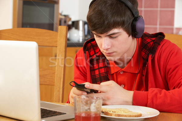 Usando la computadora portátil escuchar reproductor mp3 comer desayuno Foto stock © monkey_business