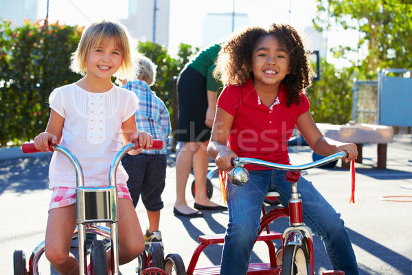 Stock photo: Two Girls Riding Tricycles In Playground