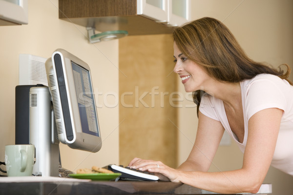 Woman in kitchen with computer smiling Stock photo © monkey_business