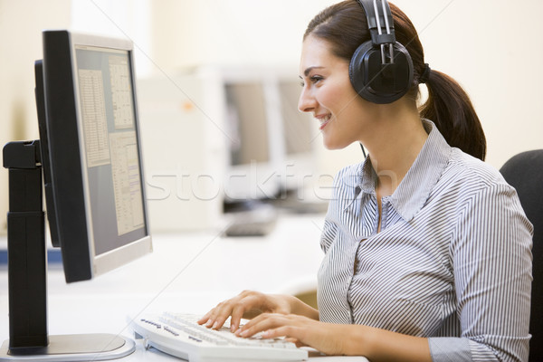 Nő visel fejhallgató számítógépszoba gépel mosolygó nő Stock fotó © monkey_business