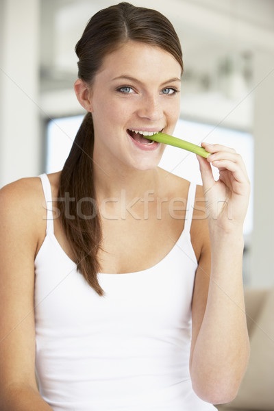 Młoda kobieta jedzenie seler kobieta domu portret Zdjęcia stock © monkey_business