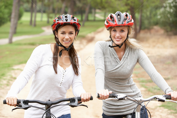 Stock photo: Two Female friends riding bikes in park