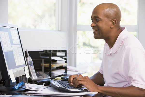 Stock photo: Man in home office using computer and smiling