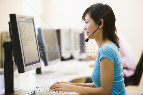 Woman wearing headset in computer room typing and smiling Stock photo © monkey_business