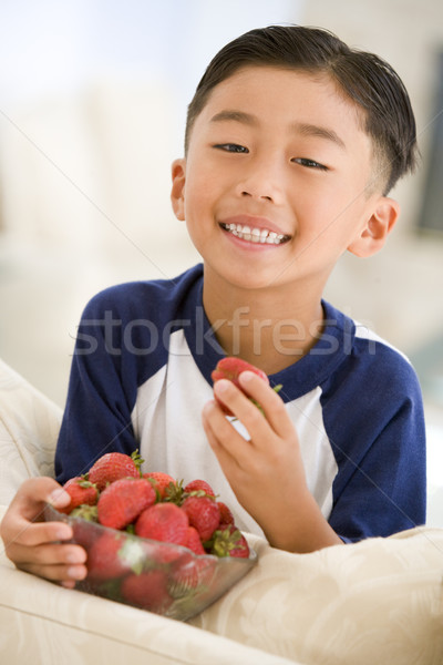 Stock photo: Young boy eating strawberries in living room smiling